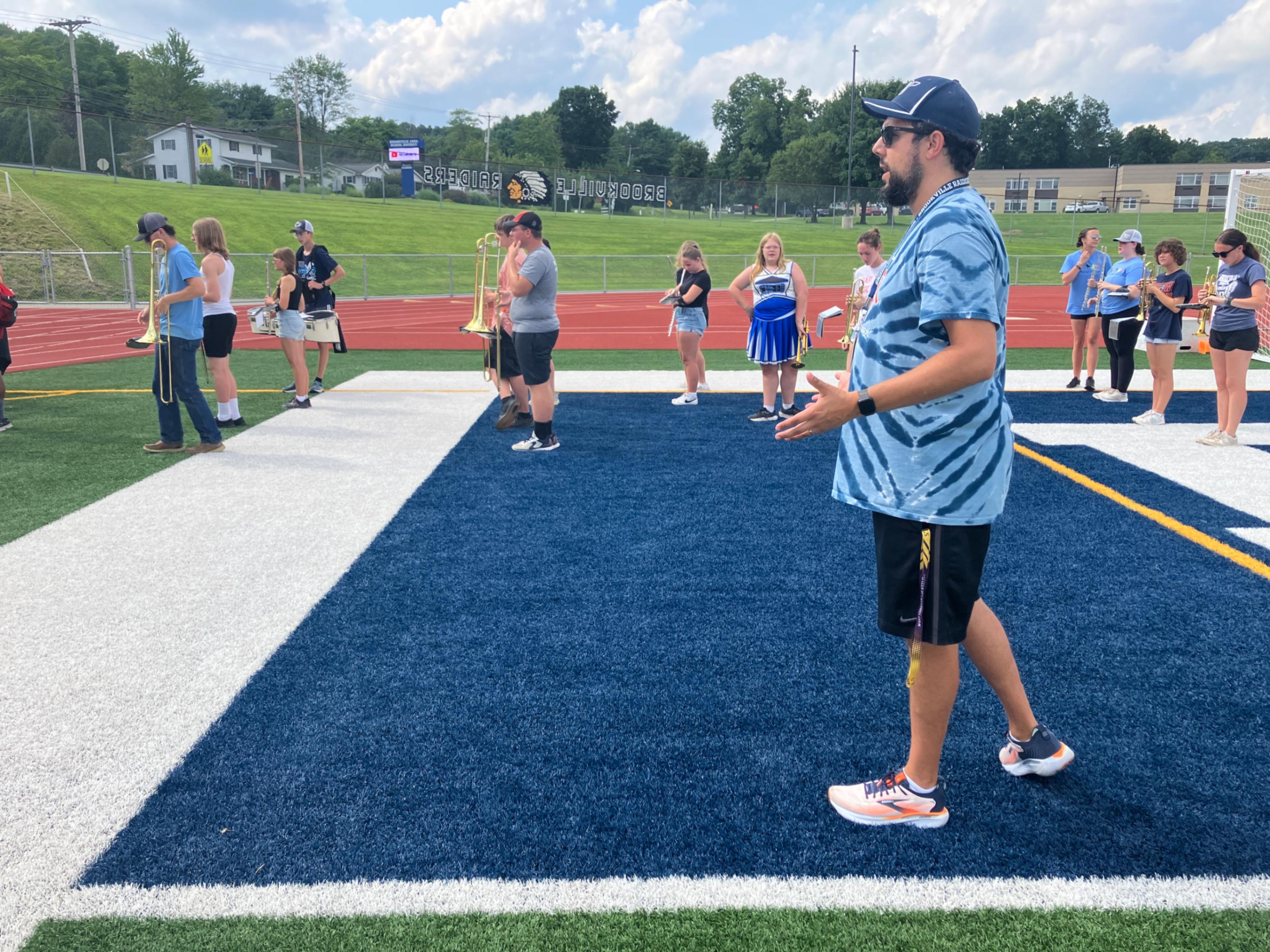 Band director, Kyle Grabigel, directs members of the marching band during practice on the football field.